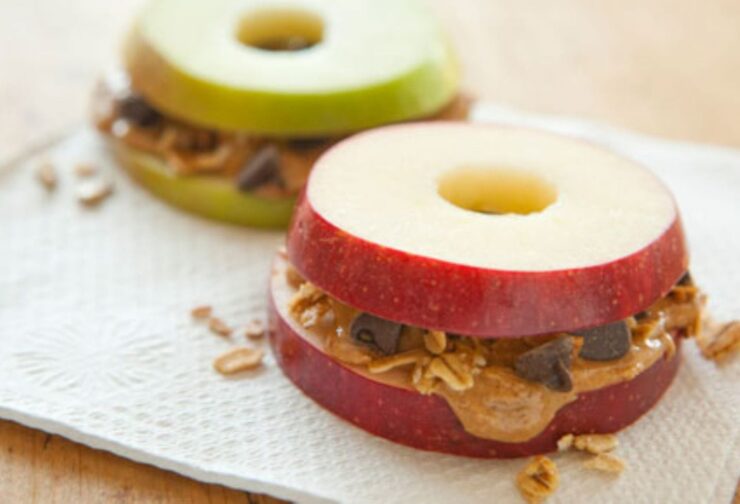 Apple slices sandwiching seed butter and granola